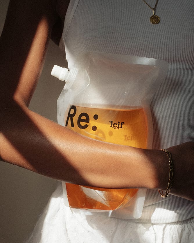 A woman holding a Leif 1L ReFill to her torso
