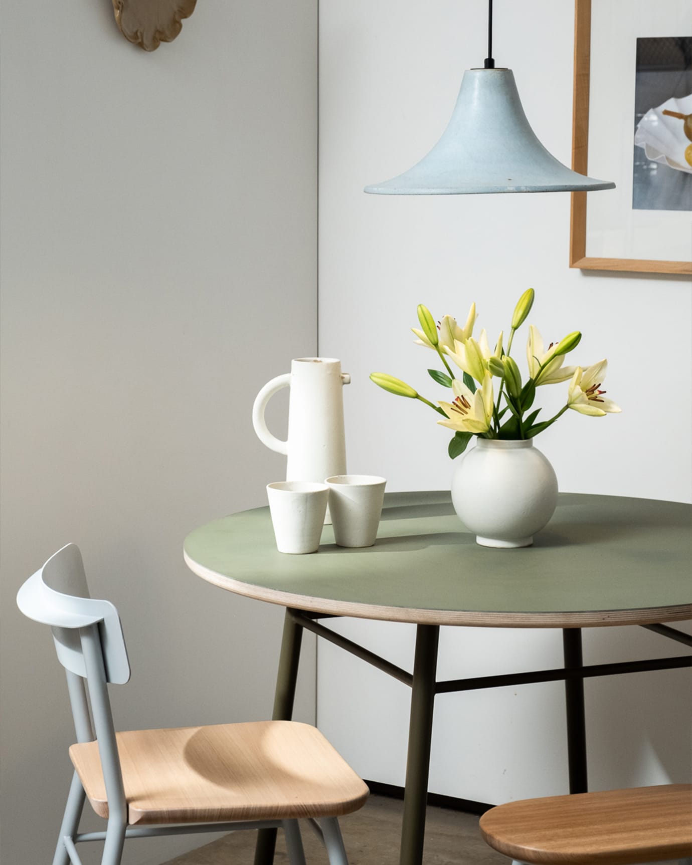 A dining area at the JamFactory featuring a pendant, table, chair, vase and ceramics in a pastel colour scheme.