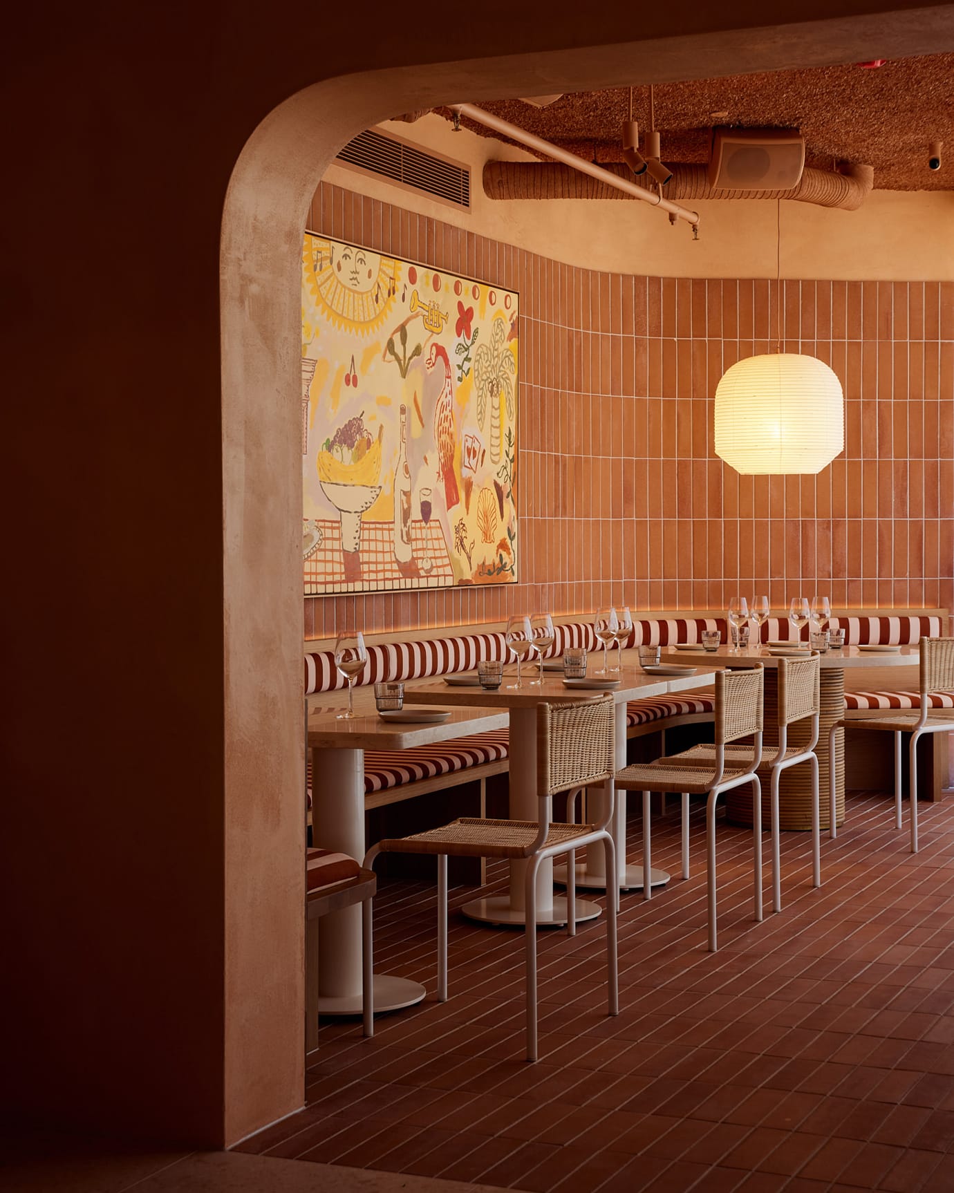 The interior of Light Years restaurant, Byron Bay, featuring colourful artwork, bench seats and a paper pendant light