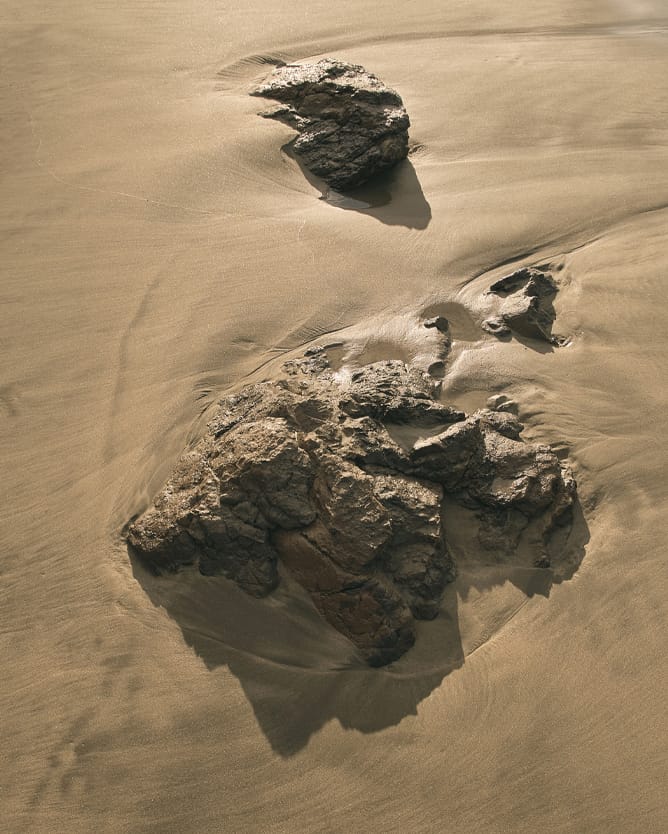 A rock covered by wet sand at the beach